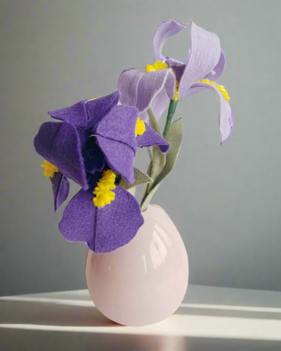 a white vase filled with purple flowers on top of a table