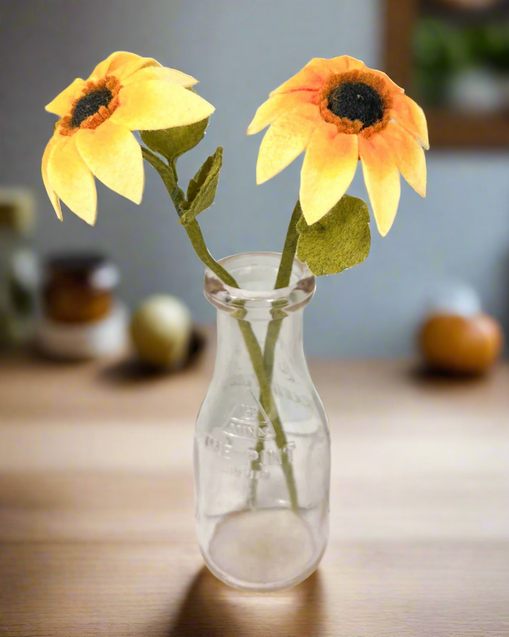 two yellow sunflowers in a clear glass vase