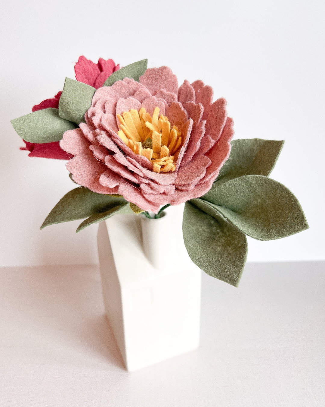 a white vase with a pink and yellow flower in it
