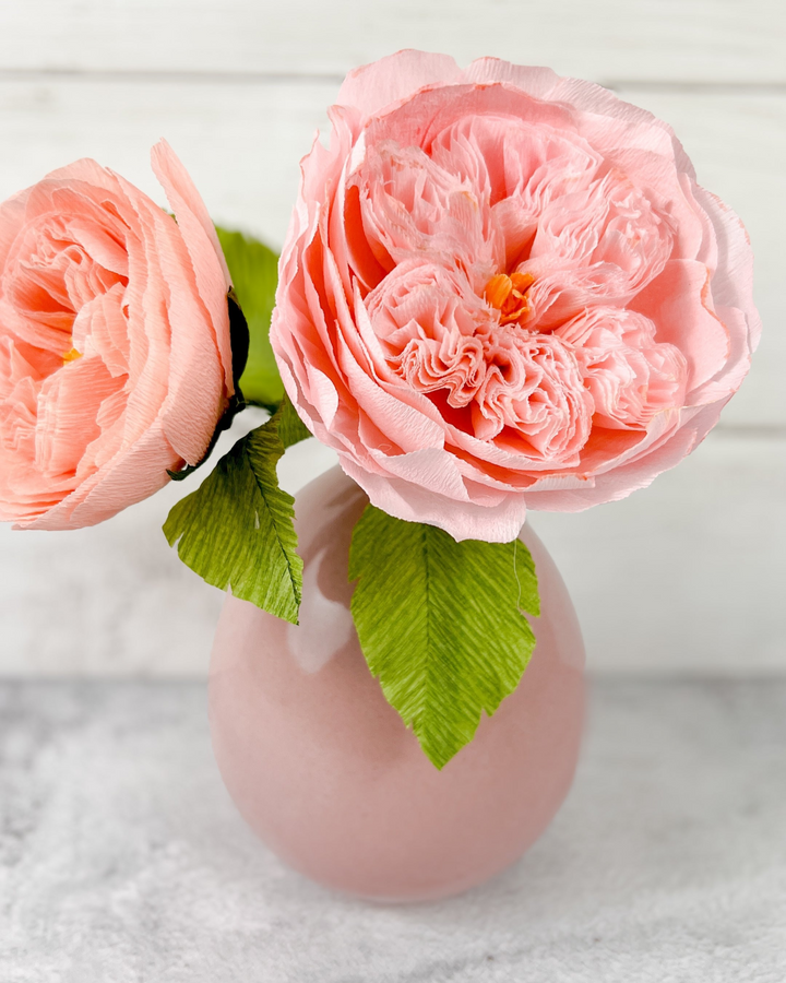a pink vase with two pink flowers in it
