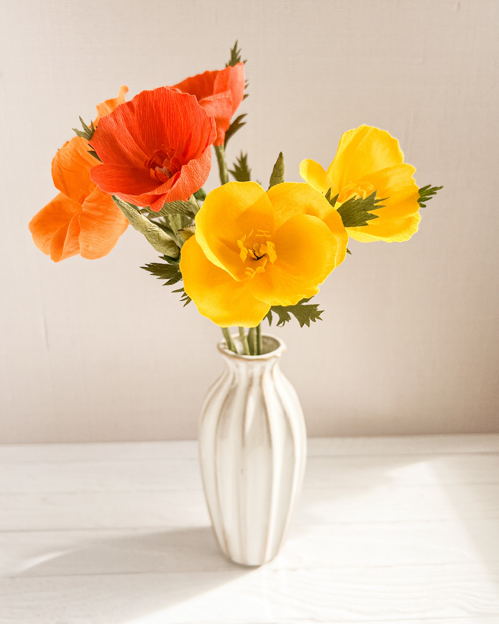 a white vase filled with orange and yellow flowers