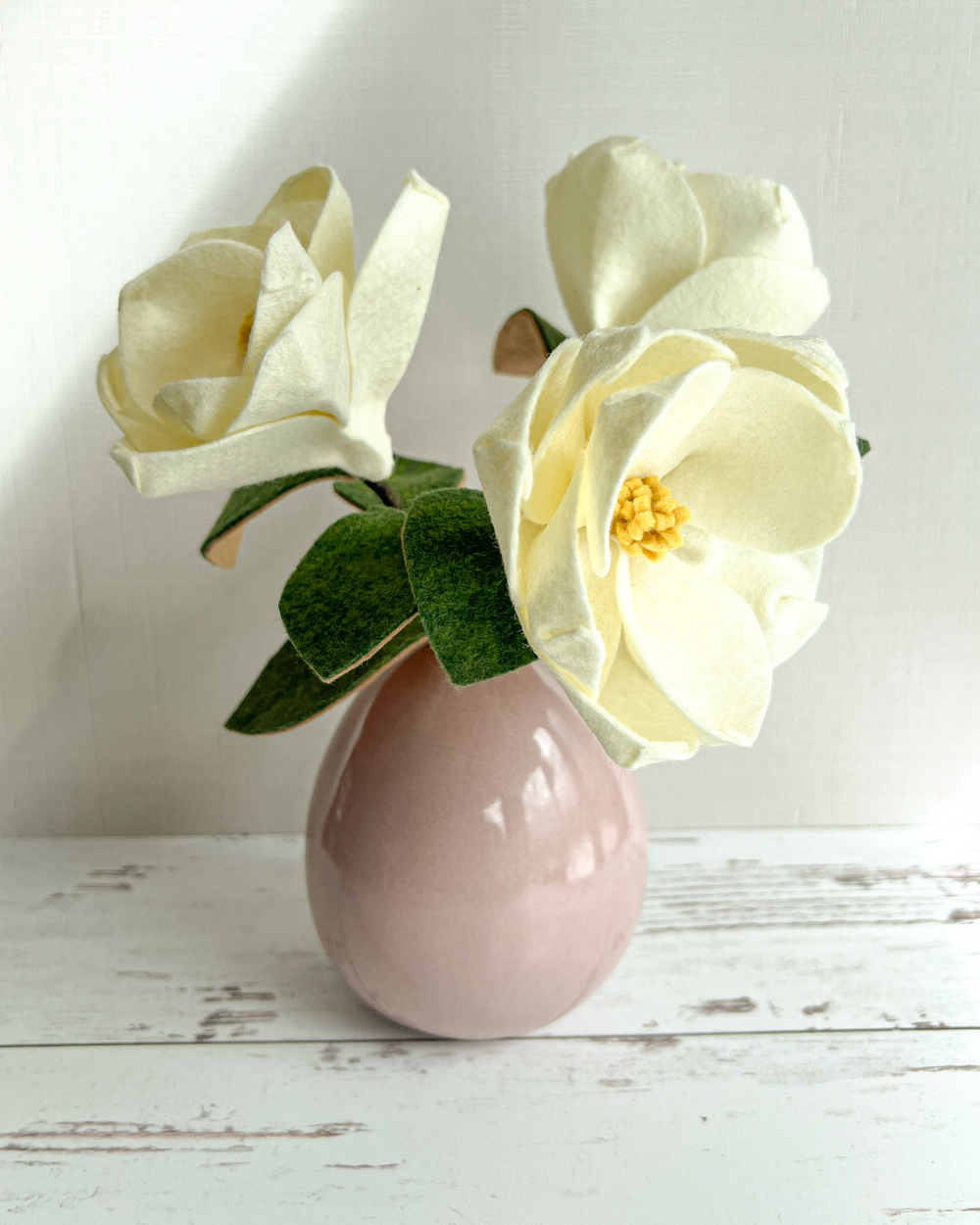 a pink vase with two white flowers in it