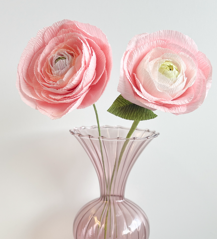 a pink vase with three pink flowers in it