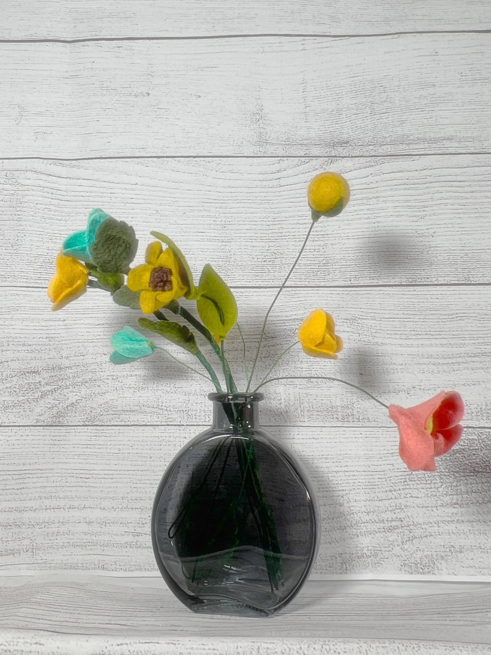 a black vase filled with yellow and red flowers