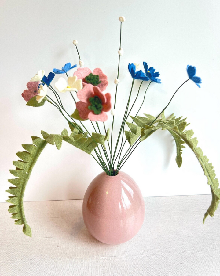 a pink vase filled with flowers on top of a table