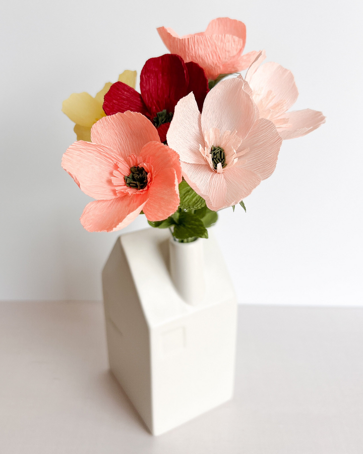 a white vase filled with flowers on top of a table