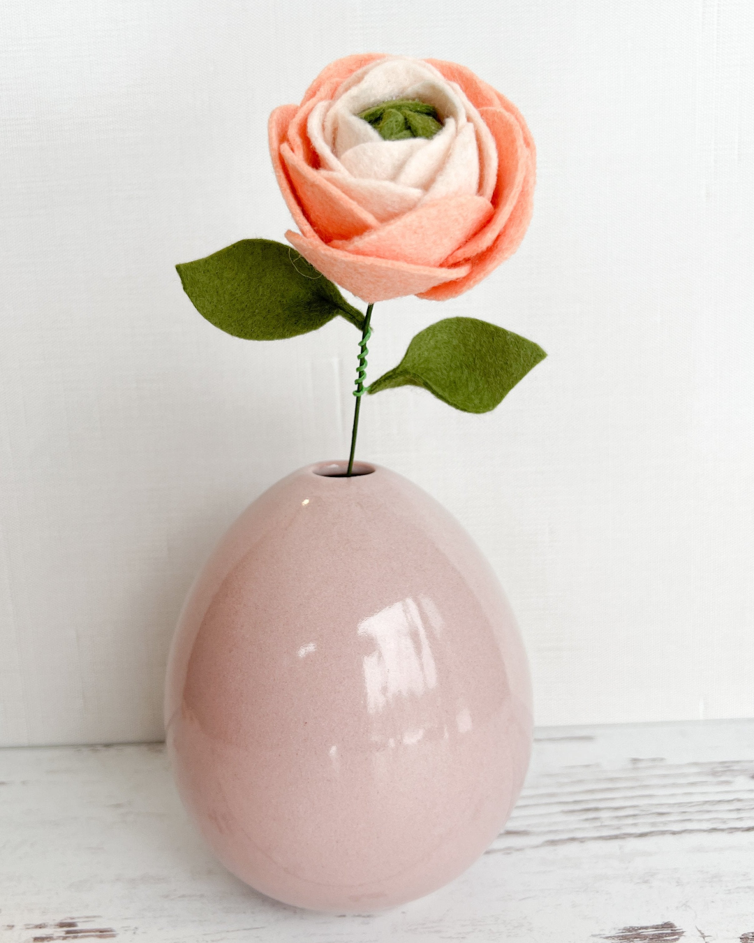 a pink vase with a single flower in it