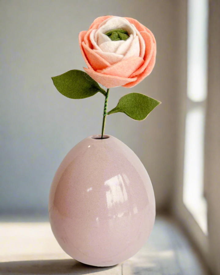 a pink vase with a single flower in it
