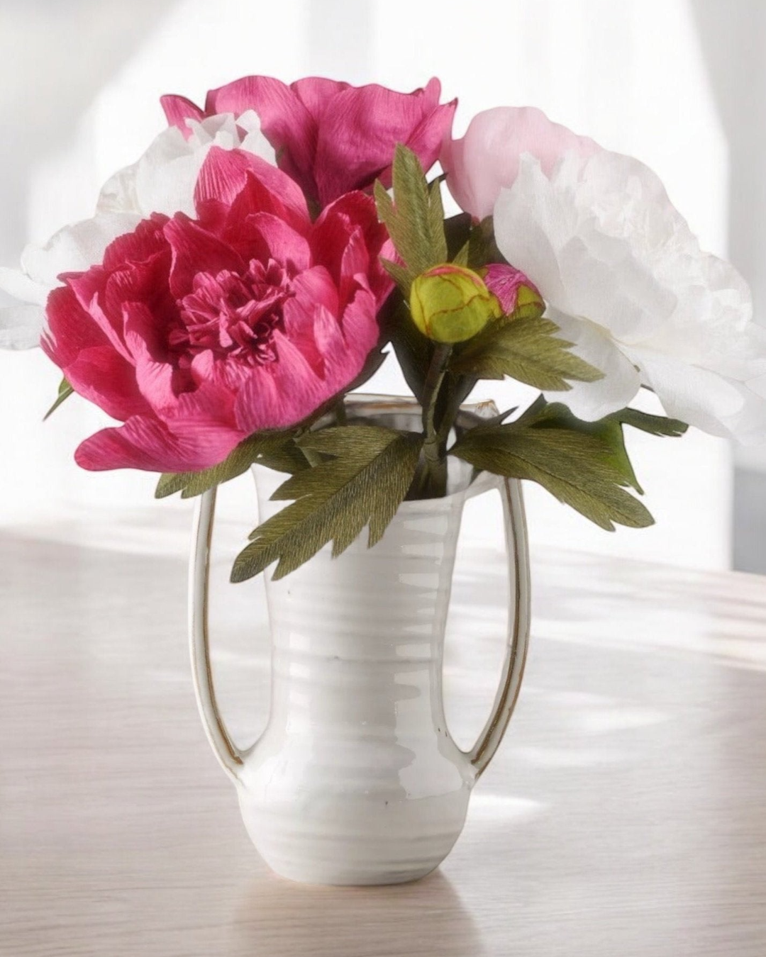a white vase filled with pink and white flowers