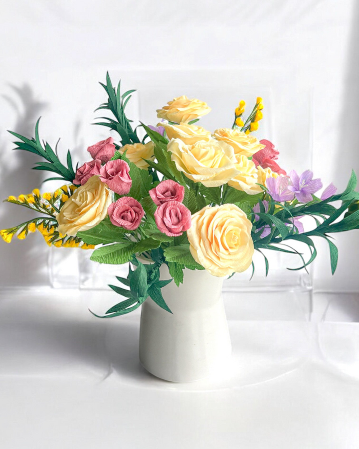 a white vase filled with lots of colorful flowers