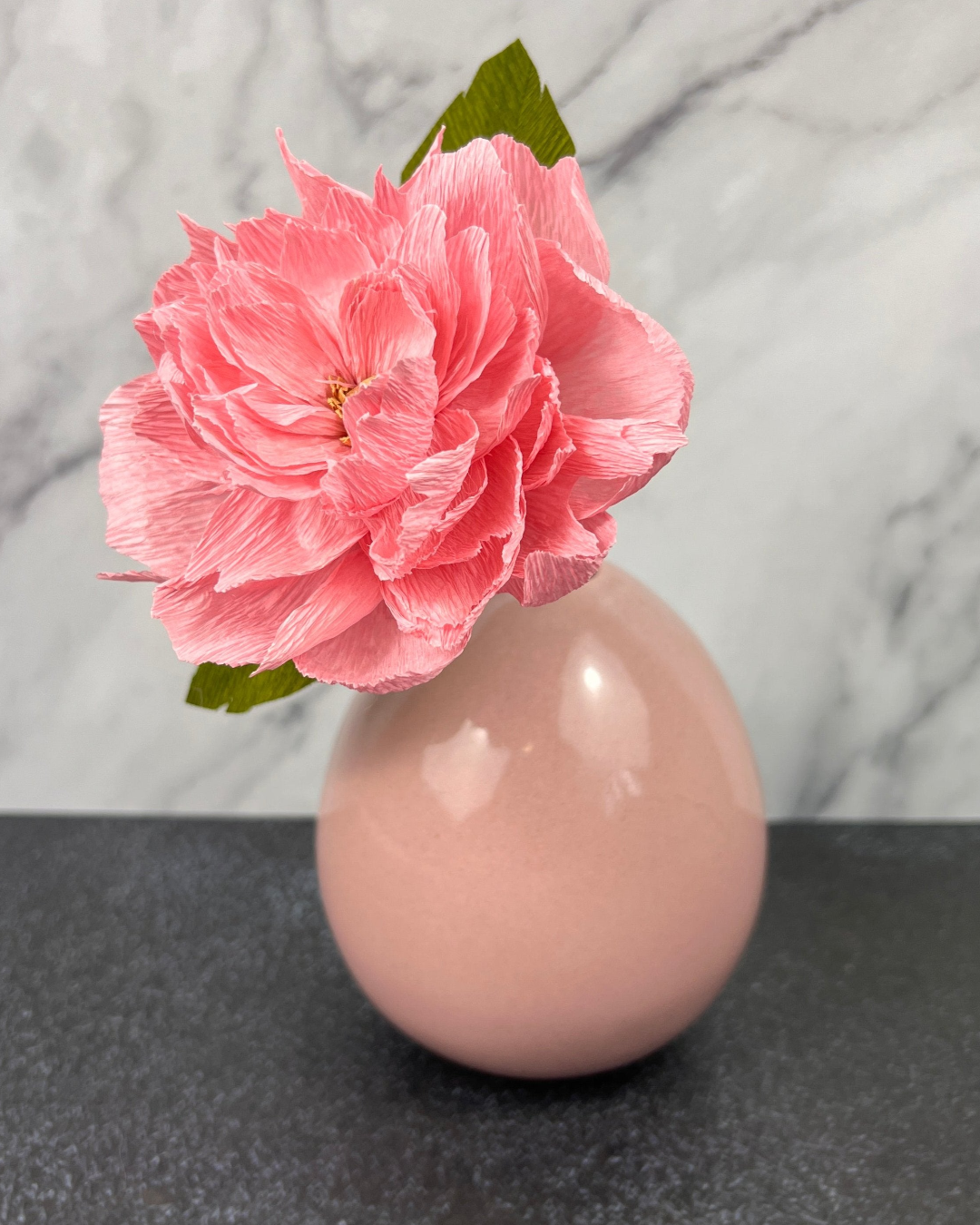 a pink vase with a pink flower in it