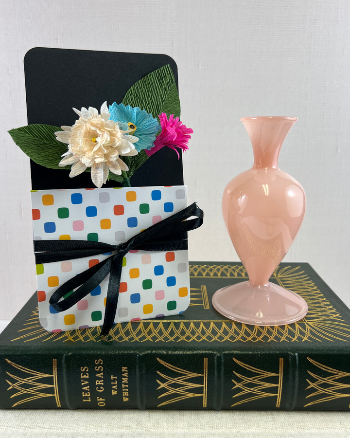 a pink vase sitting on top of a book