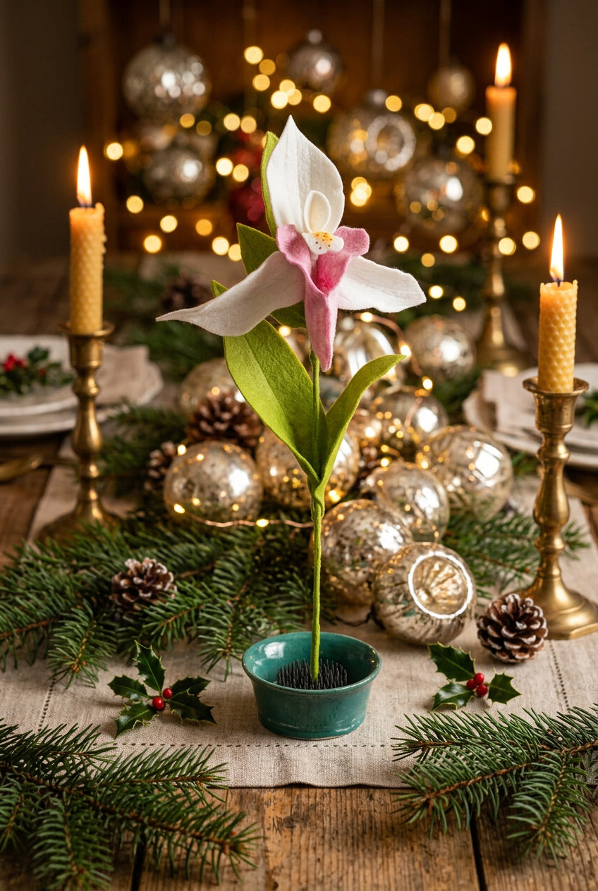 A single artificial Lady Slipper Stem with white and pink petals, green leaves, and a green stem, displayed in a small green pot against a soft pastel background.