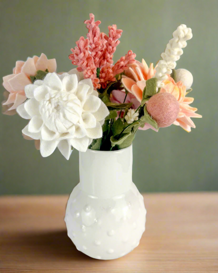 a white vase filled with lots of different colored flowers