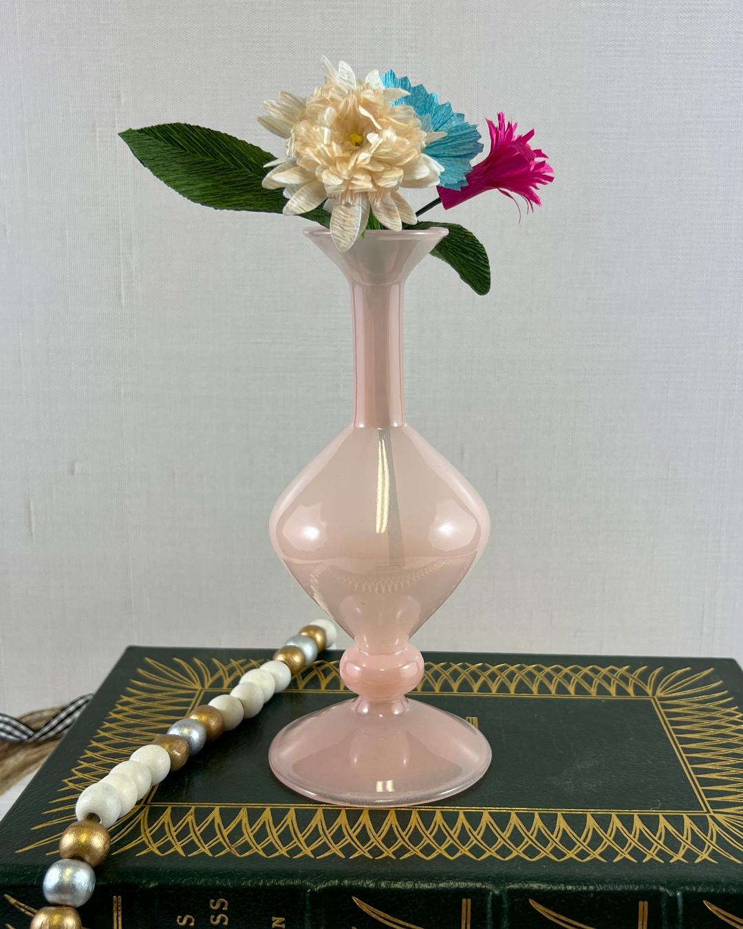 a pink vase sitting on top of a book