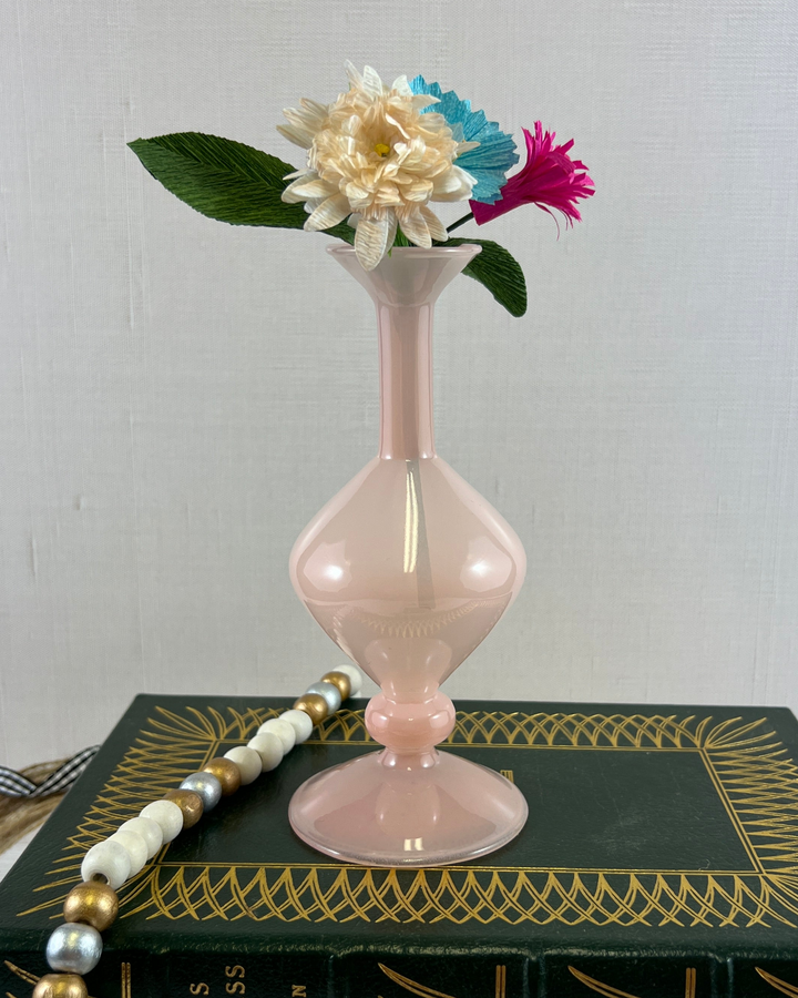 a pink vase sitting on top of a book