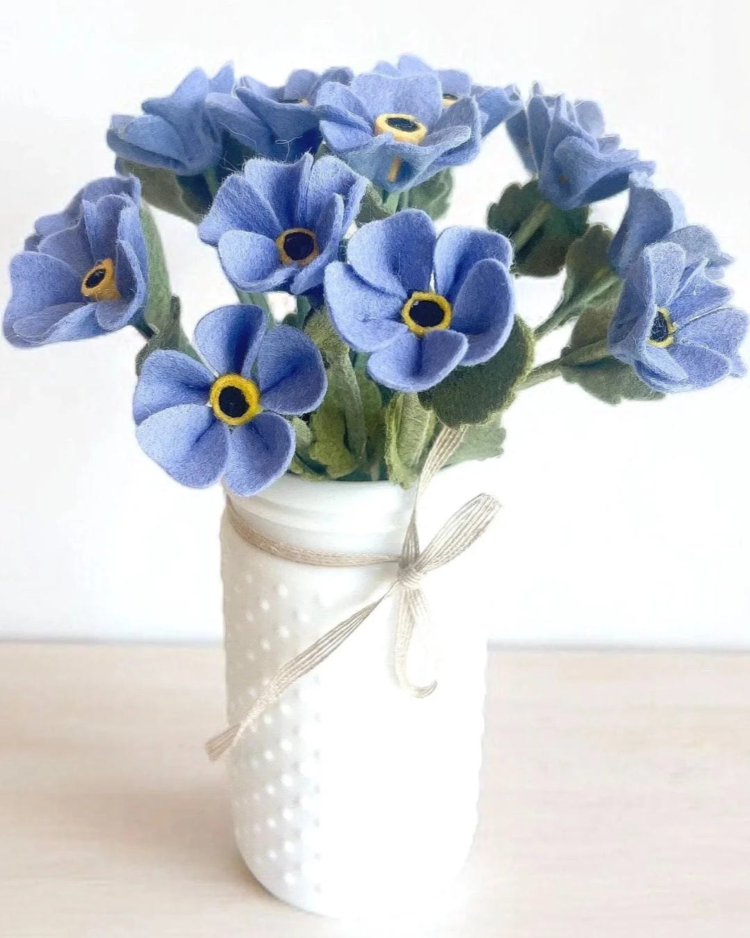 a white vase filled with blue flowers on top of a table