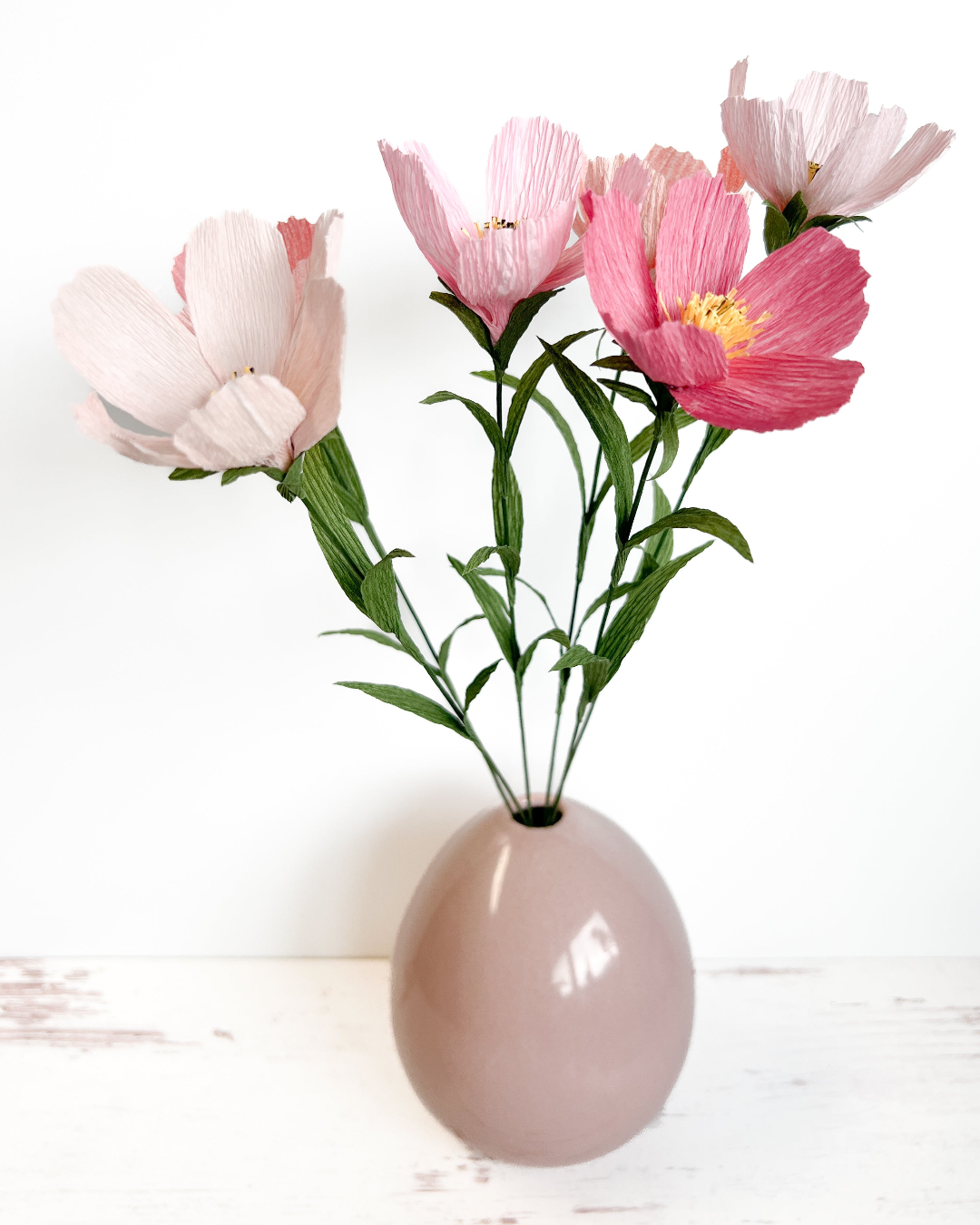 three pink flowers in a vase on a table
