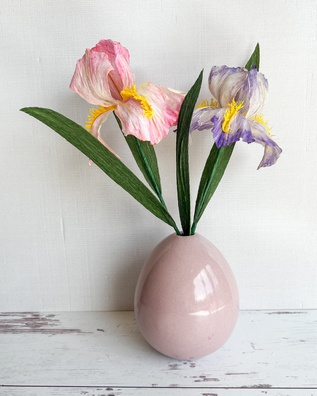 a pink vase filled with flowers on top of a white table