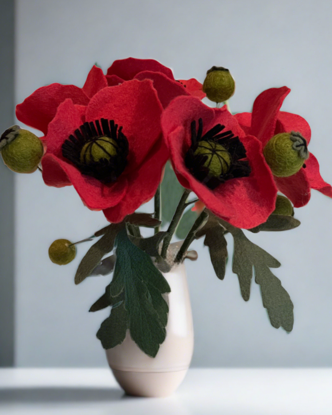 a white vase filled with red flowers on top of a table