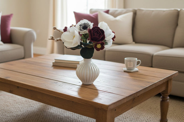 Melly Meier Botanicals handcrafted felt flower bouquet in deep burgundy and white on a wooden coffee table.