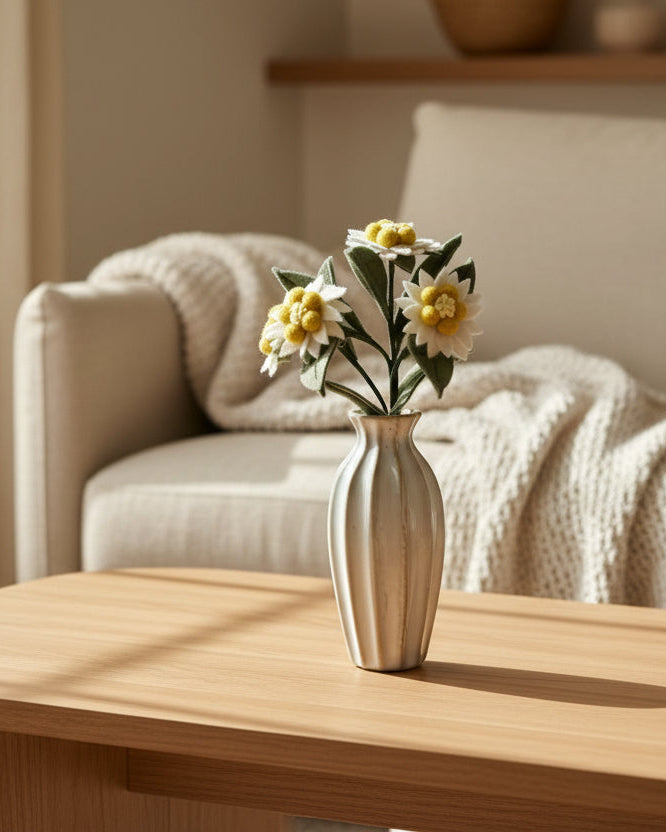 Melly Meier Botanicals handcrafted felt edelweiss stem with four white and yellow blooms in a ribbed ceramic vase.
