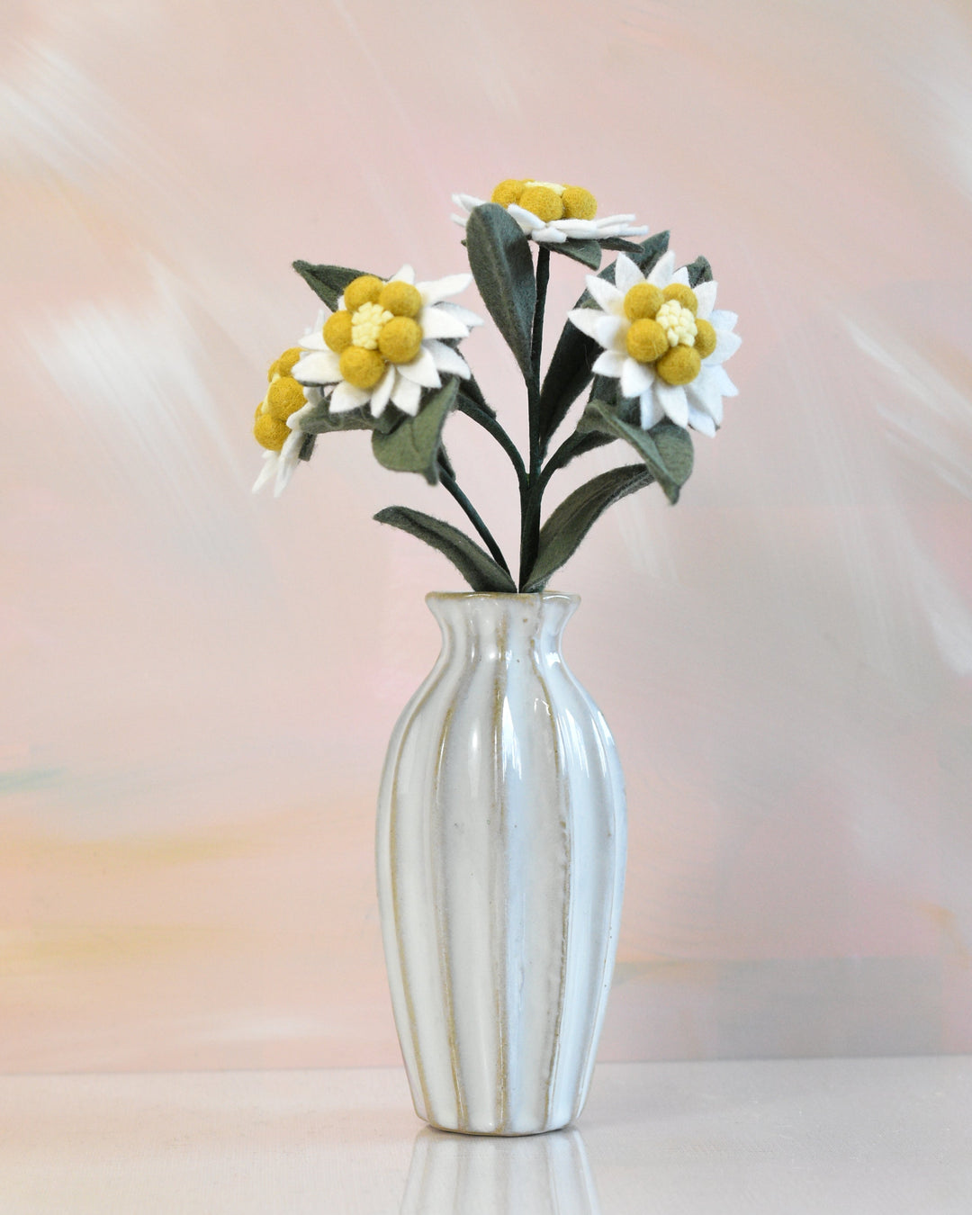 Melly Meier Botanicals handcrafted felt edelweiss stem with white and yellow wool flowers in a ribbed ceramic vase.