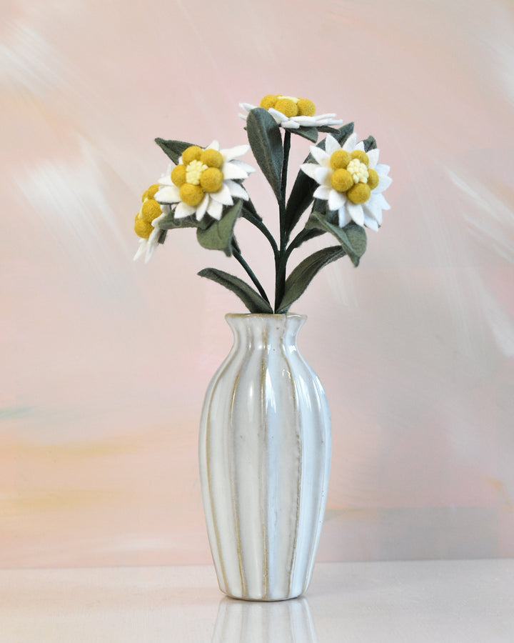 Melly Meier Botanicals handcrafted felt edelweiss stem with white and yellow wool flowers in a ribbed ceramic vase.