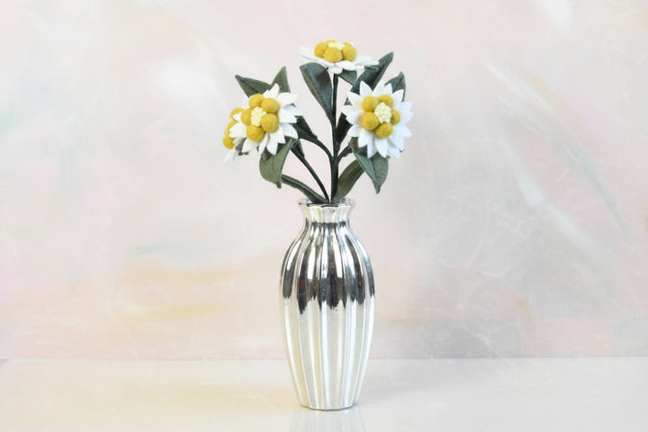 Melly Meier Botanicals handcrafted felt edelweiss stem with white and yellow wool blooms in a silver ribbed vase