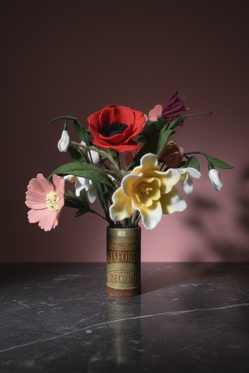 Melly Meier Botanicals bouquet of felt flowers including red poppy, yellow daffodil, pink blossom, and white snowdrops in a vintage Oxford Record tin.