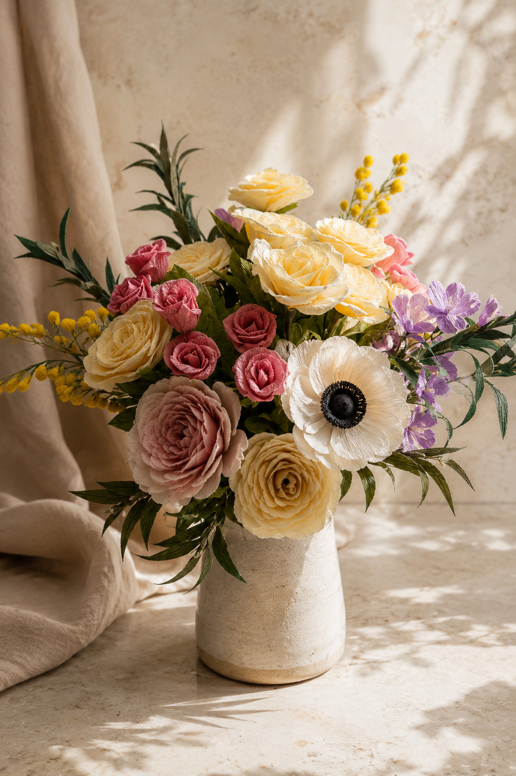 Bouquet of paper flowers in a white vase on a textured surface with soft lighting